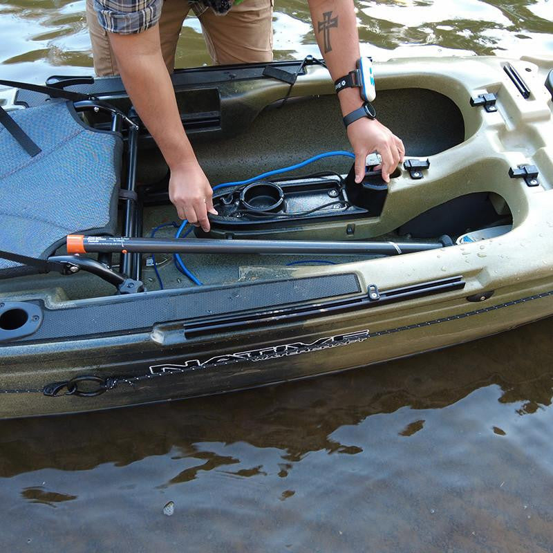 Close-up, top-down view of a person connecting a blue cable to a Bixpy mounting base inside a Native kayak in murky water.