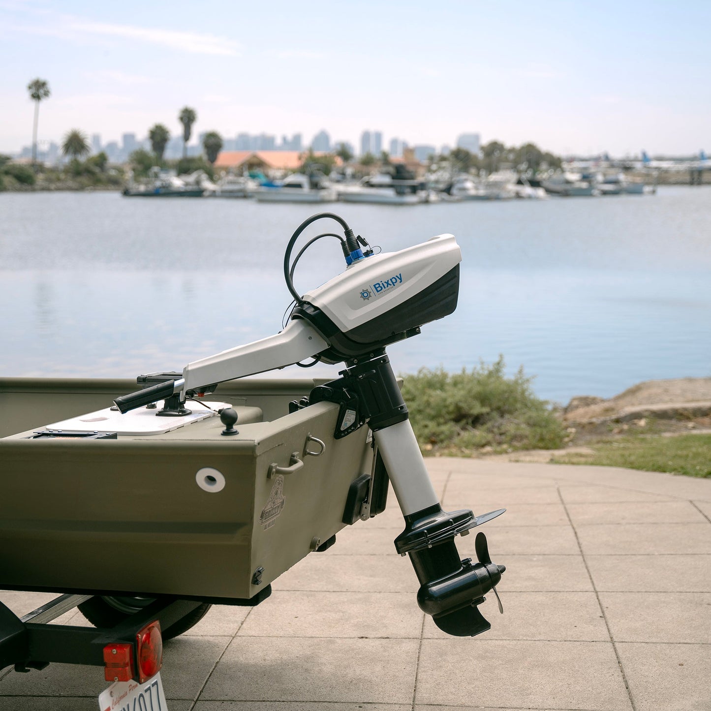 An outboard motor on a small boat with a waterfront background.