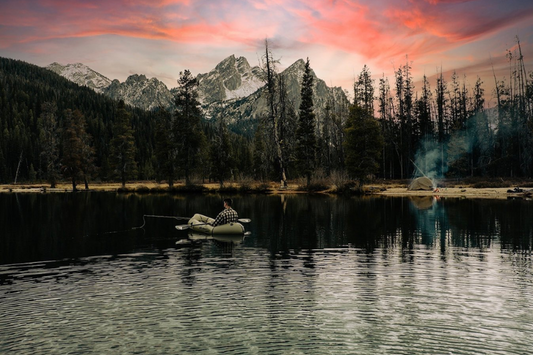 Man in inflatable boat featuring a Bixpy K-1 motor fishing in a mountain lake