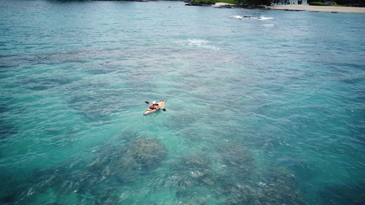 person sits in kayak with Bixpy motor as they paddle out to sea