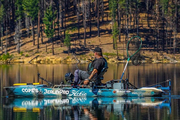 Man sits in Hobie Kayak with fishing gear heading out with the help of a Bixpy Canada K-1