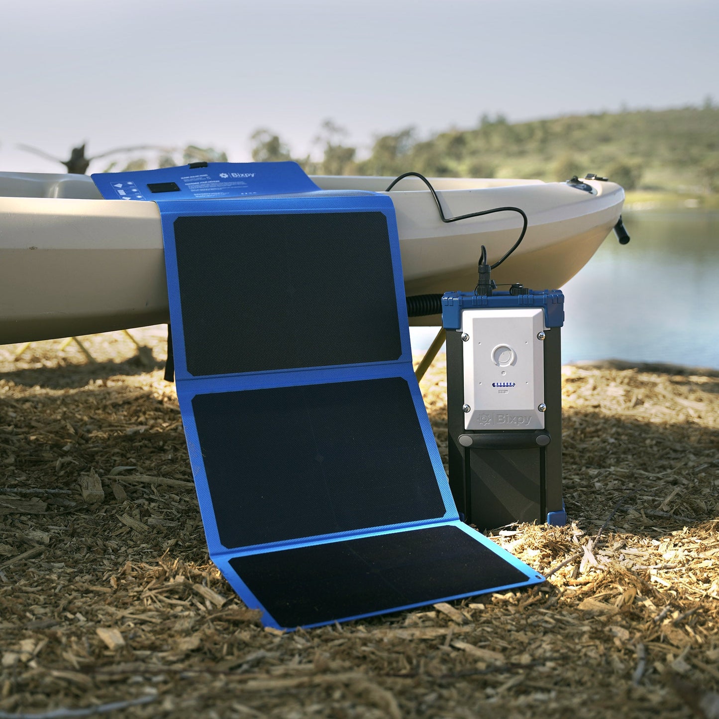 Solar panel and Bixpy PP-768 Battery on a grassy area near a body of water