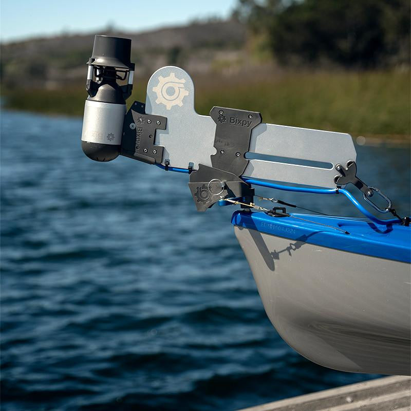 Bixpy Jet electric motor mounted on a light gray Bixpy Versa Rudder at the stern of a white and blue boat in calm water with distant trees.