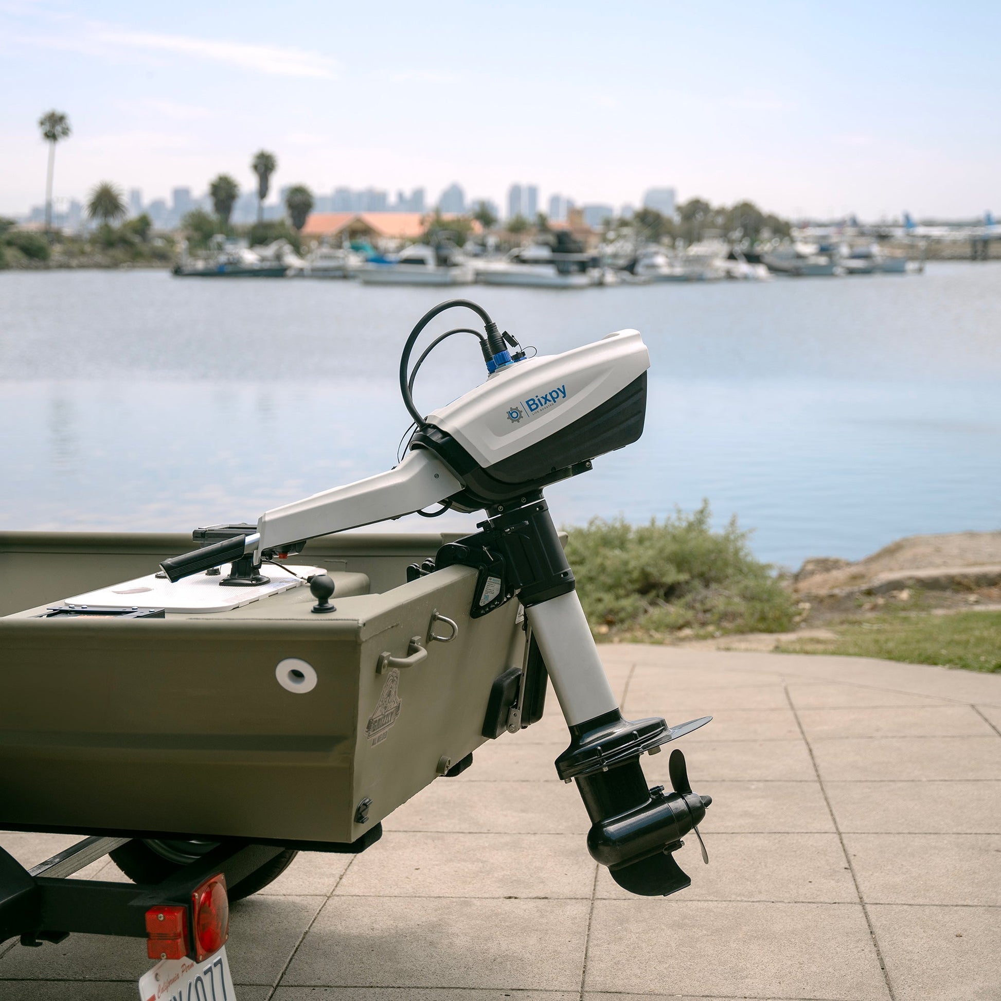 An outboard motor on a small boat with a waterfront background.